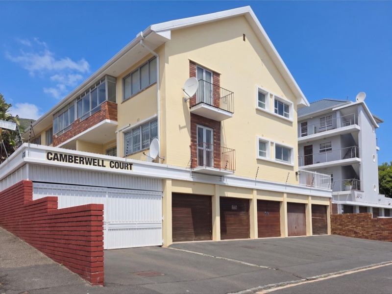 Exterior view of Camberwell Court apartment building featuring a brick and painted facade, multiple balconies, and ground-level garage access.