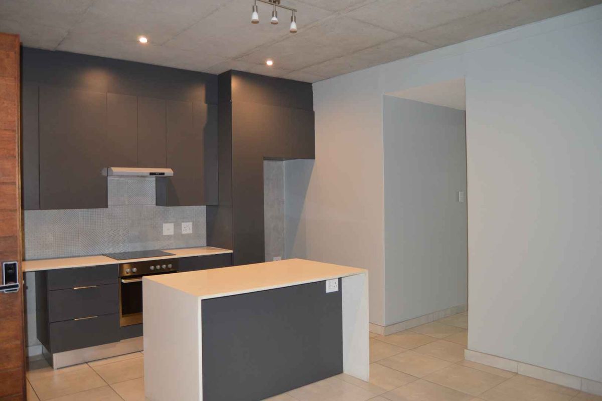 Modern kitchen featuring dark grey cabinetry, a central island, built-in appliances, mosaic backsplash, and an industrial-style exposed concrete ceiling.