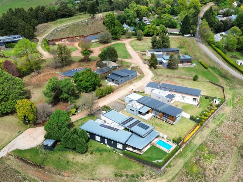 Aerial view of a residential estate featuring multiple modern homes with solar panels, landscaped gardens, and a swimming pool.