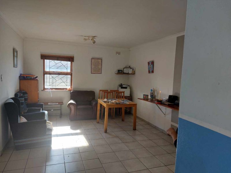 A living area featuring tiled flooring and a window with security bars, offering a functional space with potential for cosmetic updates.