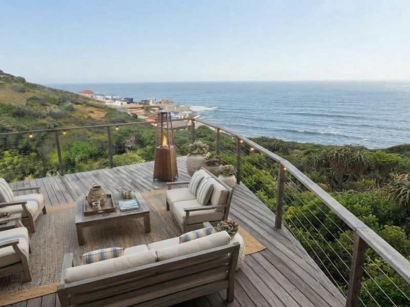 An elevated timber deck balcony featuring stainless steel cable railings and expansive, unobstructed ocean views.