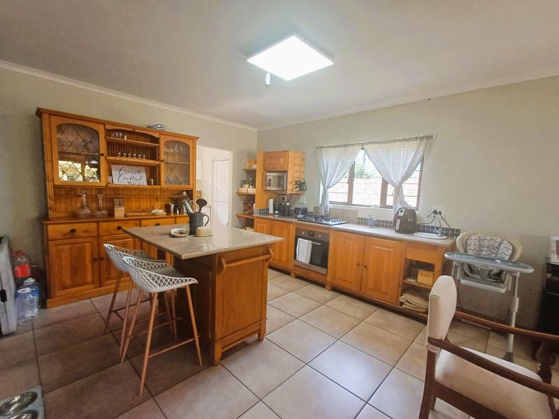 A functional kitchen featuring wooden cabinetry, granite countertops, a central island, and built-in cooking appliances with ceramic tiled flooring.
