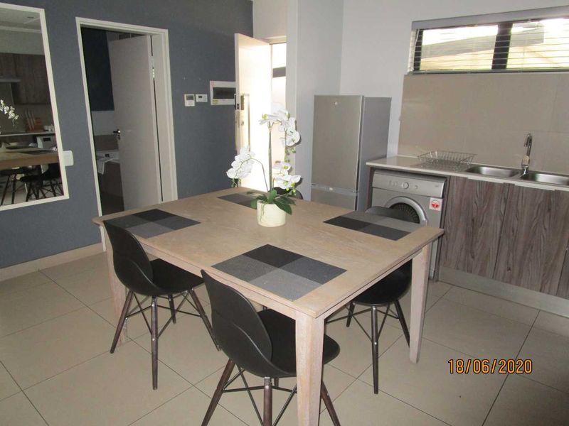Open plan kitchen and dining area featuring tiled flooring, built-in cabinetry, and a double sink, providing a functional living space.