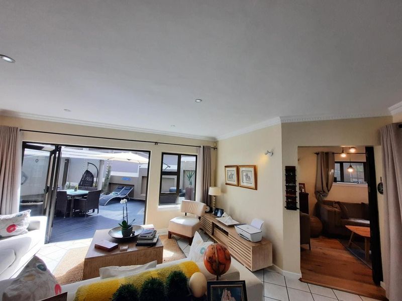 Spacious open-plan living area featuring tiled and timber flooring, recessed lighting, and seamless bi-fold door access to an outdoor patio space.
