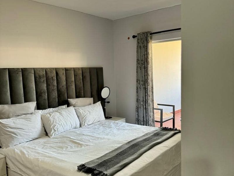 A well-maintained bedroom featuring laminate flooring, a flush mount ceiling light, and direct access to an outdoor balcony area.