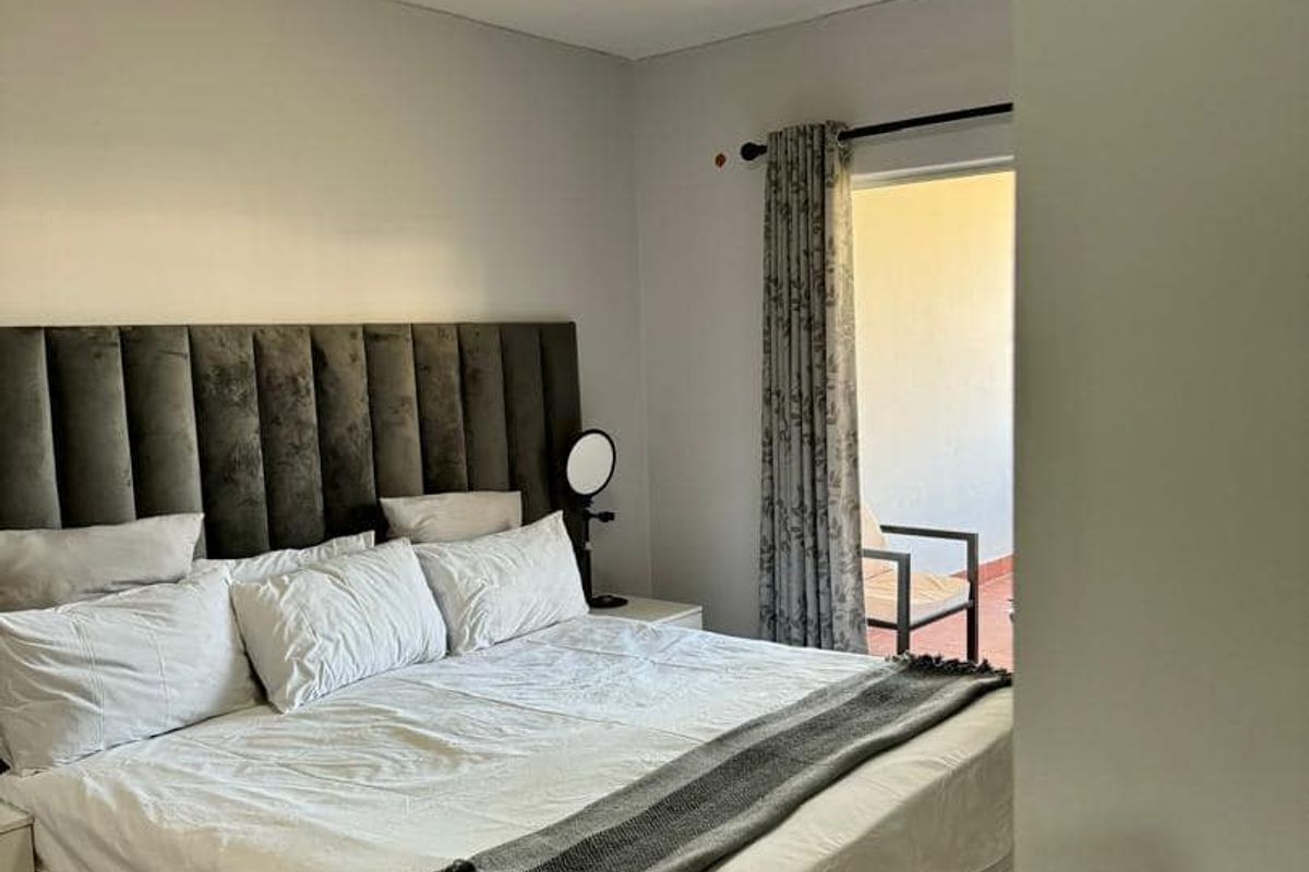 A well-maintained bedroom featuring laminate flooring, a flush mount ceiling light, and direct access to an outdoor balcony area.