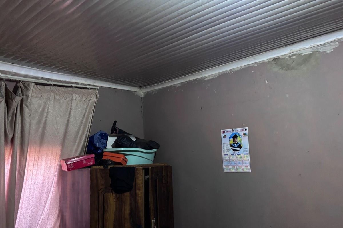 A bedroom interior featuring a corrugated ceiling and walls showing signs of significant wear, including cracking and potential moisture damage.