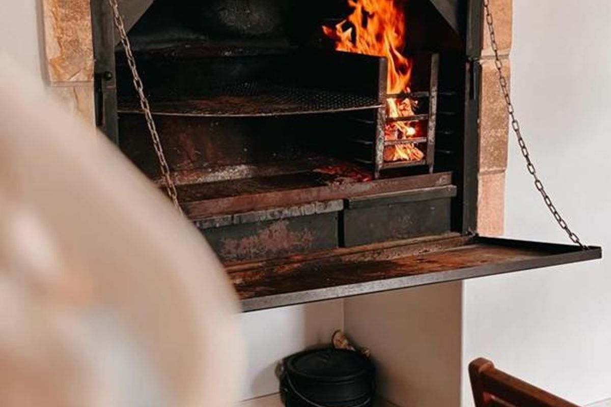 Indoor built-in braai fireplace with stone surround and metal firebox, featuring a functional hearth and integrated cooking grate.