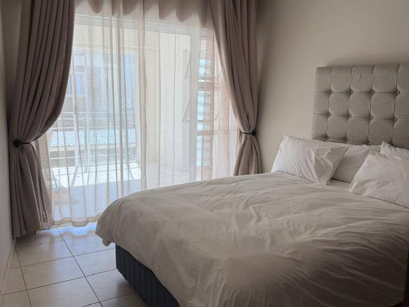 A bedroom featuring tiled flooring and a sliding glass door providing access to an outdoor area, finished with neutral wall tones.