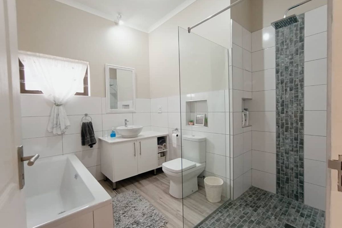 Modern bathroom featuring a glass-enclosed walk-in shower with mosaic tile accents, a freestanding bathtub, and a sleek vanity with a vessel sink.