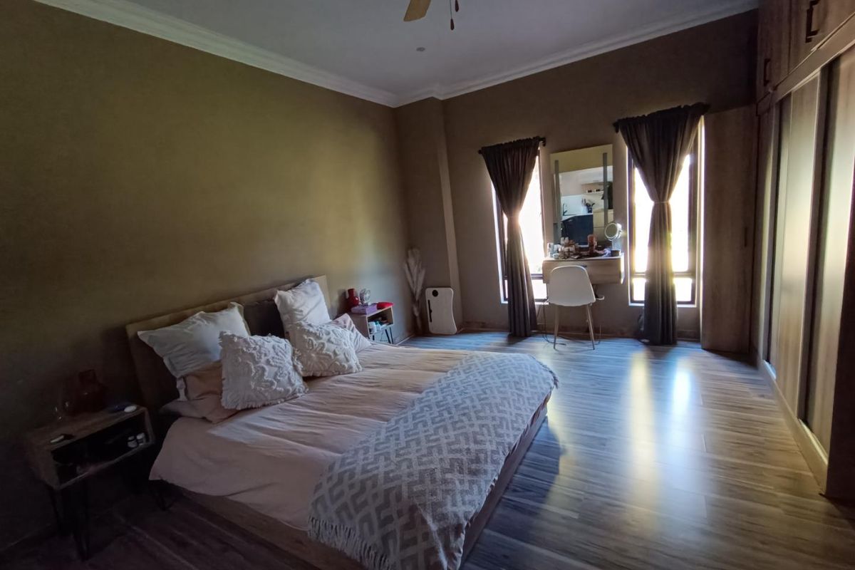 Spacious bedroom featuring wood-look laminate flooring, built-in cupboards, and a ceiling fan, offering a comfortable and well-maintained living space.