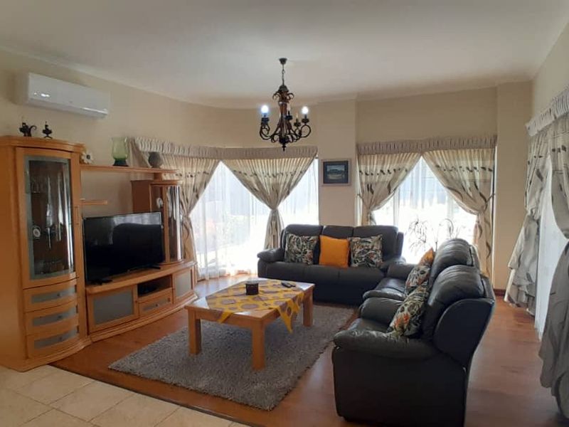 Spacious living room featuring a combination of tiled and laminate flooring, a split-system air conditioner, and decorative wall lighting.