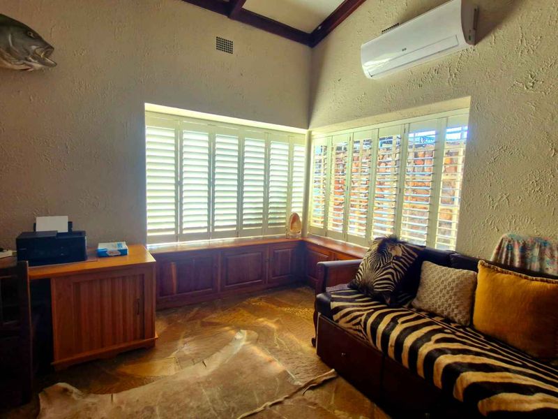 A living area featuring stone flooring, built-in window seat cabinetry with plantation shutters, and a wall-mounted split-system air conditioner.
