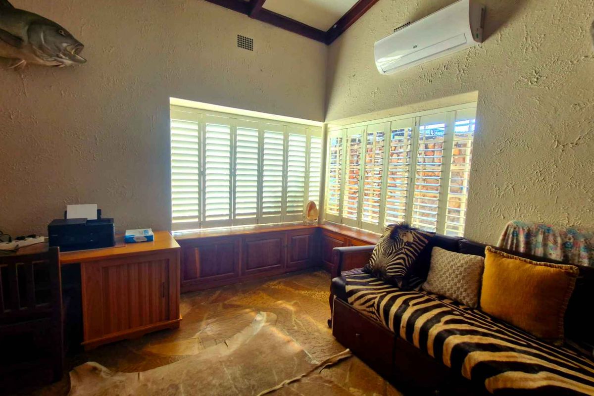 A living area featuring stone flooring, built-in window seat cabinetry with plantation shutters, and a wall-mounted split-system air conditioner.