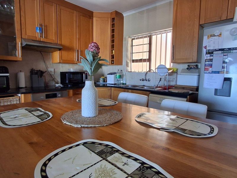 A functional kitchen featuring wooden cabinetry, laminate countertops, and integrated appliances, offering a practical layout for daily meal preparation.