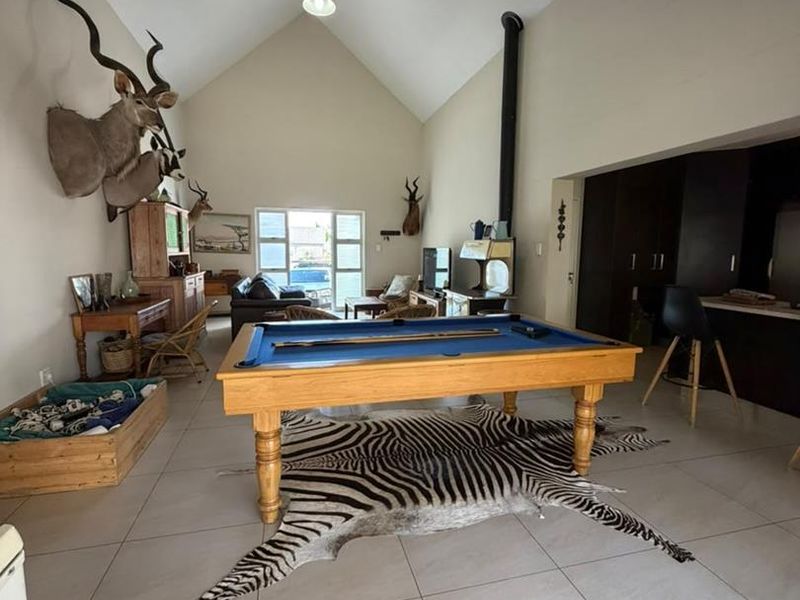 Spacious open-plan living area featuring high vaulted ceilings, tiled flooring, and a prominent freestanding fireplace, offering a versatile layout for entertainment.