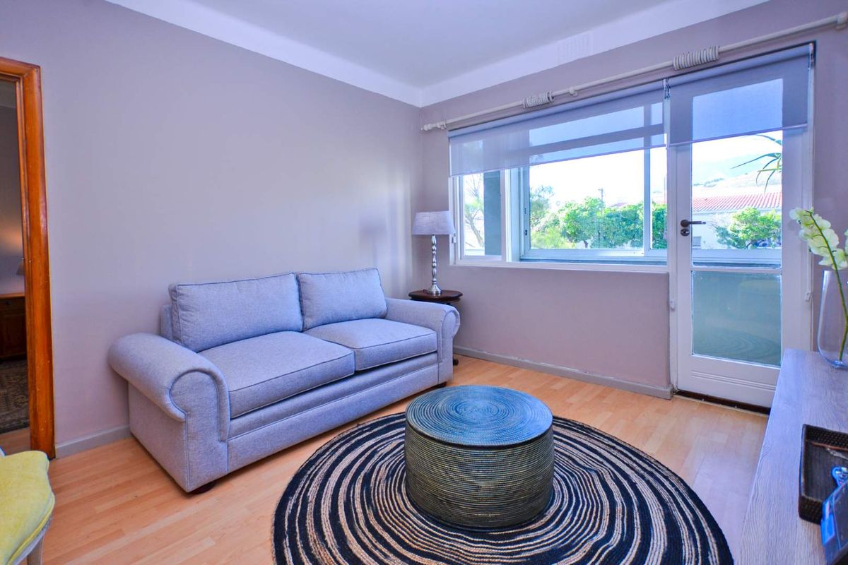A comfortable living room featuring light laminate flooring, neutral wall tones, and direct access to an outdoor area through a glass sliding door.