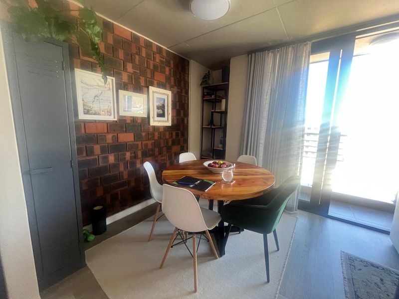 Dining area featuring a textured brick accent wall and large sliding glass doors providing natural light and access to the balcony.