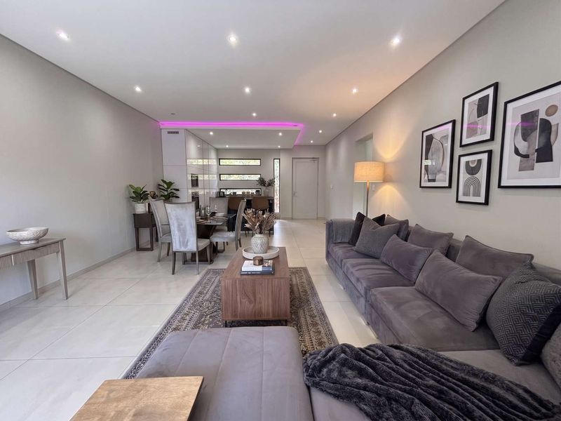 Spacious open-plan living and dining area featuring modern tiled flooring, recessed downlighting, and integrated LED accent lighting.