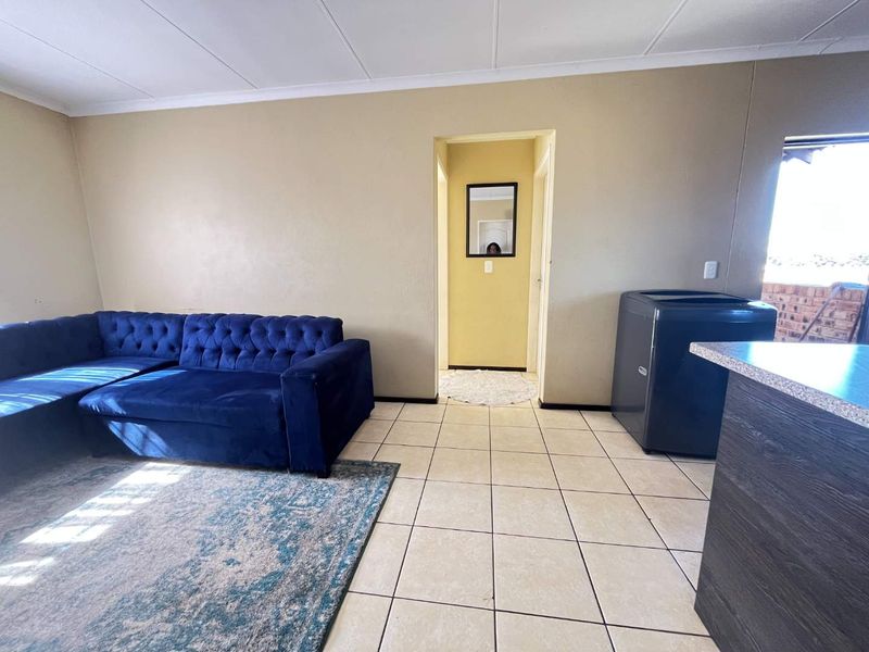 Open plan living area featuring tiled flooring and neutral wall tones, providing a functional space with direct access to the hallway.