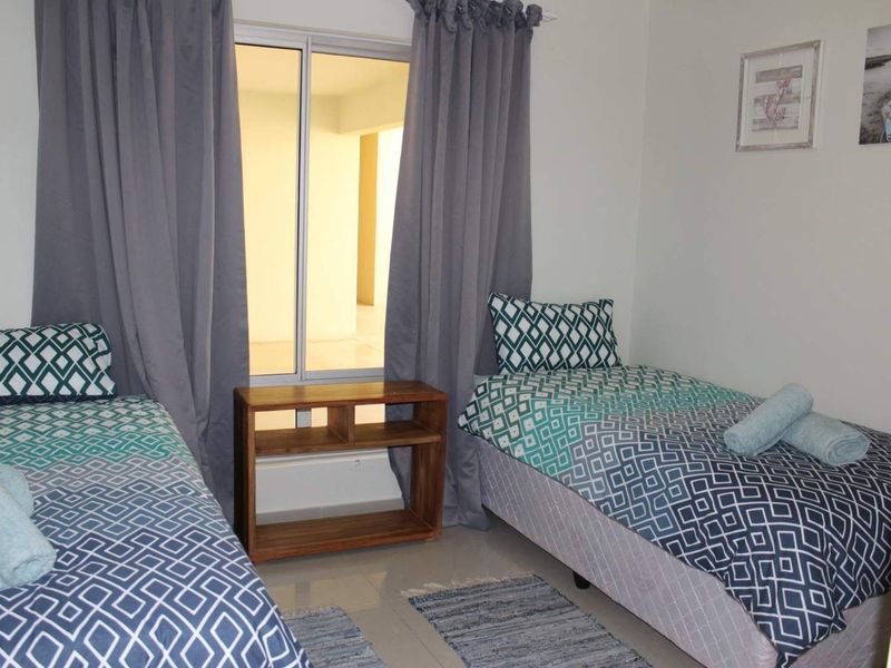 A bedroom featuring tiled flooring and a sliding window with curtains, providing natural light and access to an adjacent space.