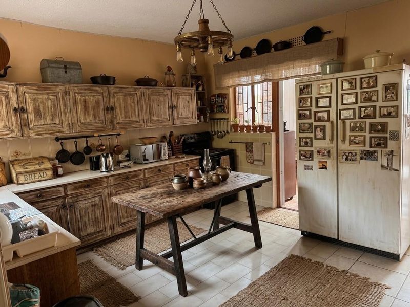 A rustic-style kitchen featuring wooden cabinetry, tiled flooring, and a central workspace, offering a warm and traditional aesthetic.
