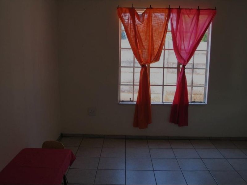 An empty living area featuring tiled flooring and a grid-pattern window, providing a blank canvas for interior design.