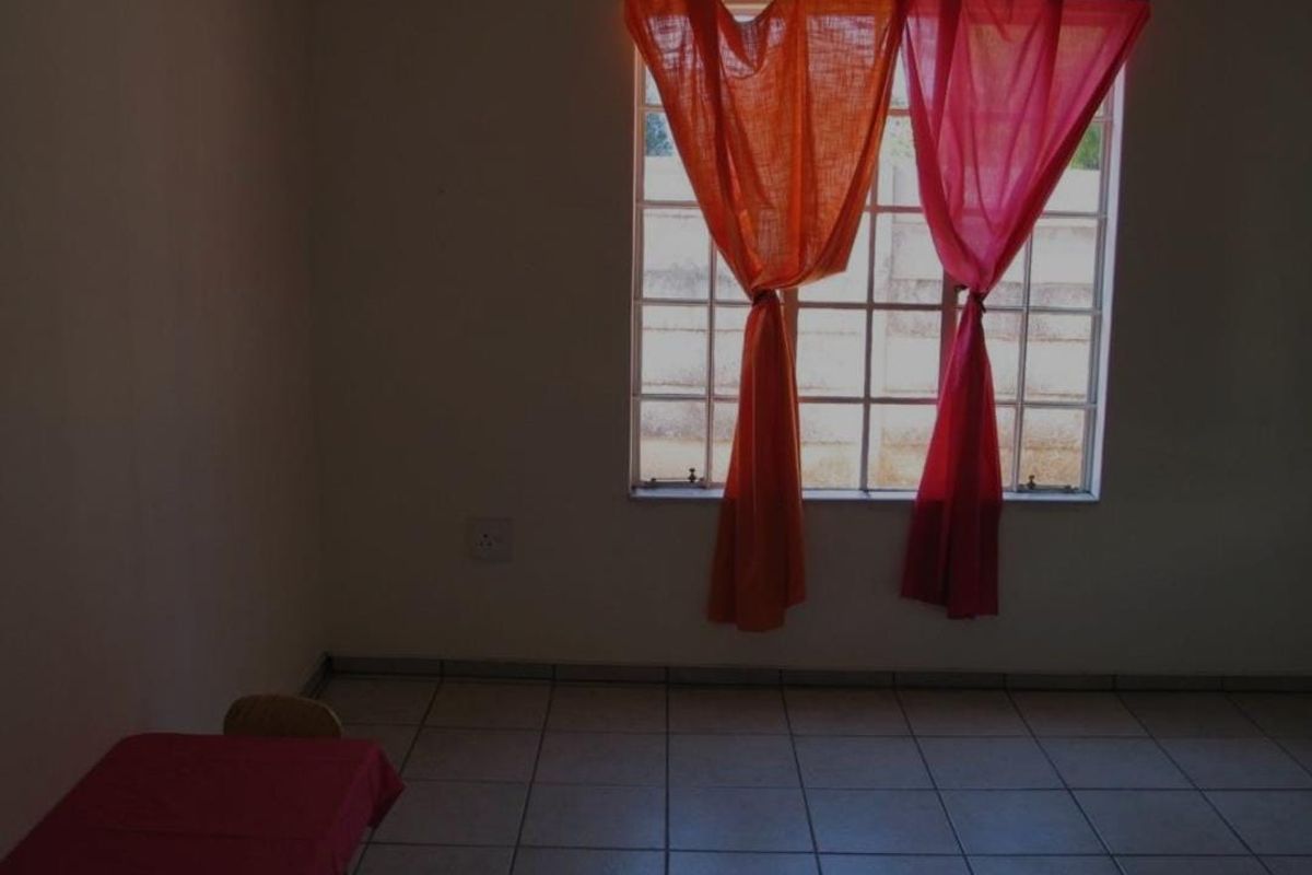An empty living area featuring tiled flooring and a grid-pattern window, providing a blank canvas for interior design.