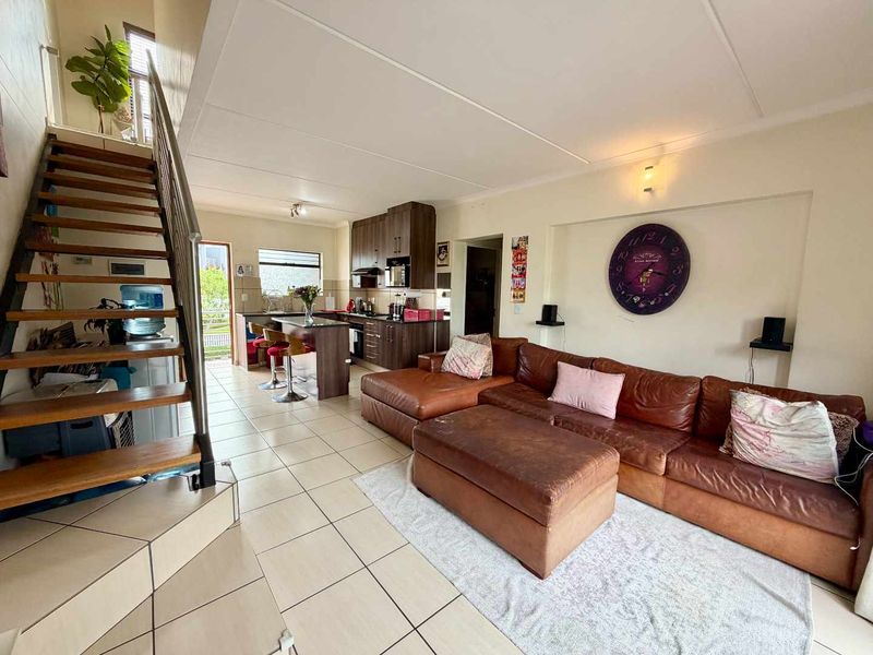 Open-plan living area featuring a kitchen with dark wood cabinetry, a central island, and a staircase leading to an upper level.