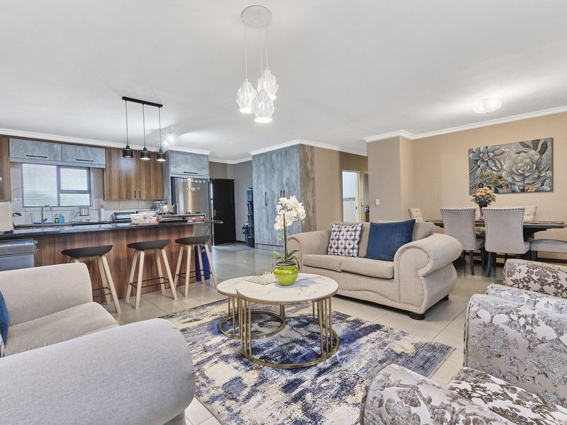 Spacious open-plan living area featuring a modern kitchen with a breakfast island, granite countertops, and integrated cabinetry, flowing into a comfortable dining and lounge space.