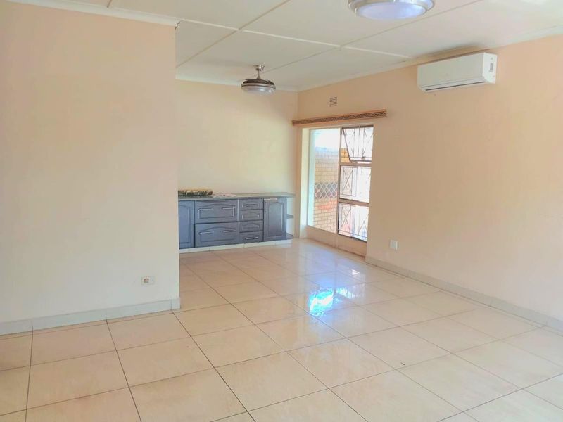 An open-plan living area featuring tiled flooring, a split-system air conditioner, a ceiling fan, and built-in cabinetry.
