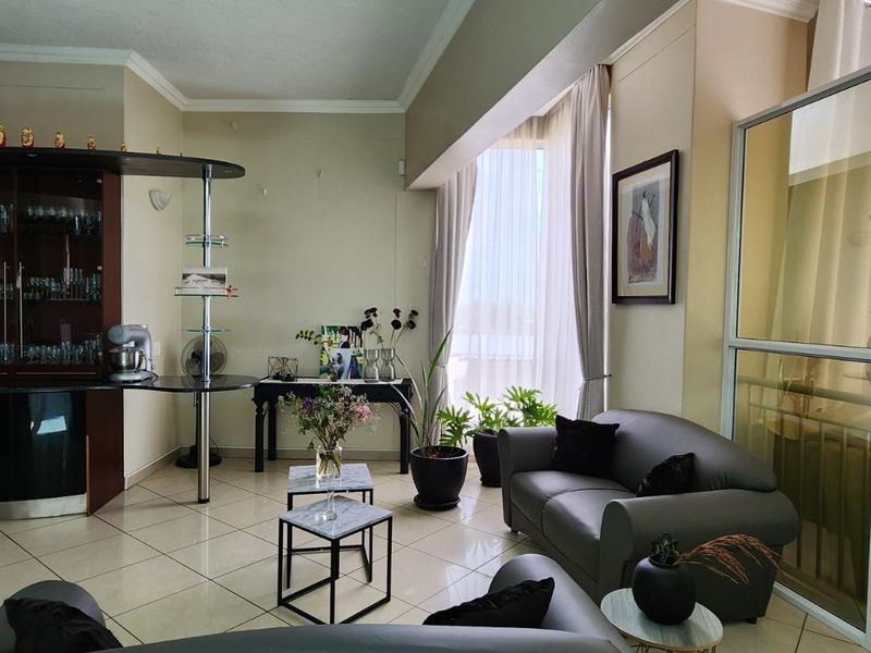 A living area featuring tiled flooring, built-in display cabinetry, and a glass partition wall, offering a bright and functional space.