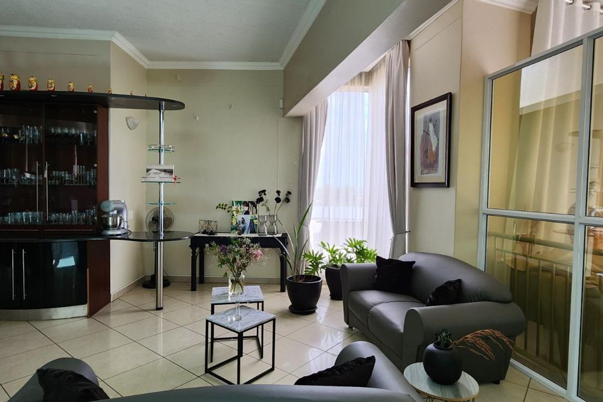 A living area featuring tiled flooring, built-in display cabinetry, and a glass partition wall, offering a bright and functional space.