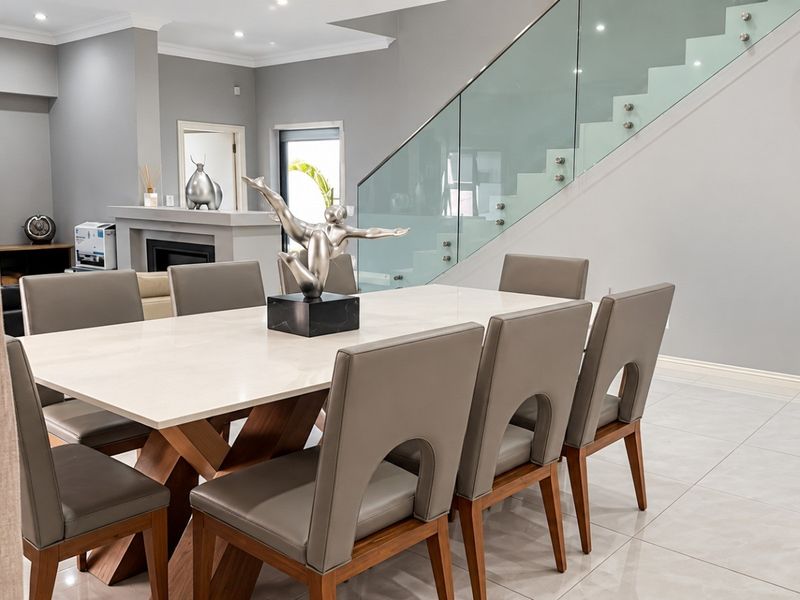 Spacious dining area featuring modern tiled flooring, recessed lighting, and a contemporary staircase with a glass balustrade, adjacent to a built-in fireplace.