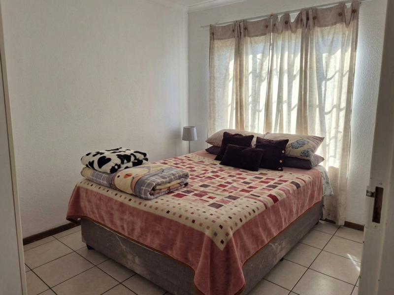 A bedroom featuring tiled flooring and a window with installed curtain rods, providing a functional space for rest.