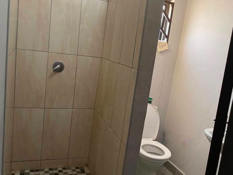 A functional bathroom featuring a tiled shower enclosure, a standard toilet, and a wash basin with neutral wall finishes.