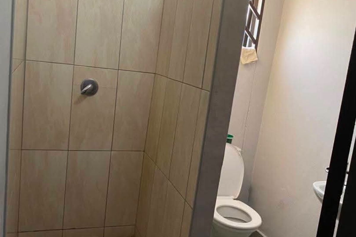 A functional bathroom featuring a tiled shower enclosure, a standard toilet, and a wash basin with neutral wall finishes.
