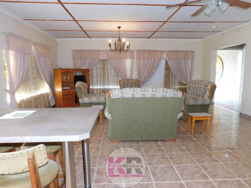 Open plan living area featuring tiled flooring, exposed ceiling beams, and a central chandelier, providing a functional and spacious layout.