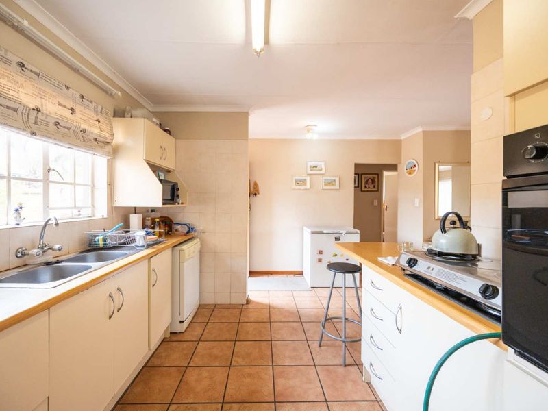 Functional kitchen featuring tiled flooring, laminate countertops, double basin sink, built-in oven, and gas hob with ample cabinetry for storage.