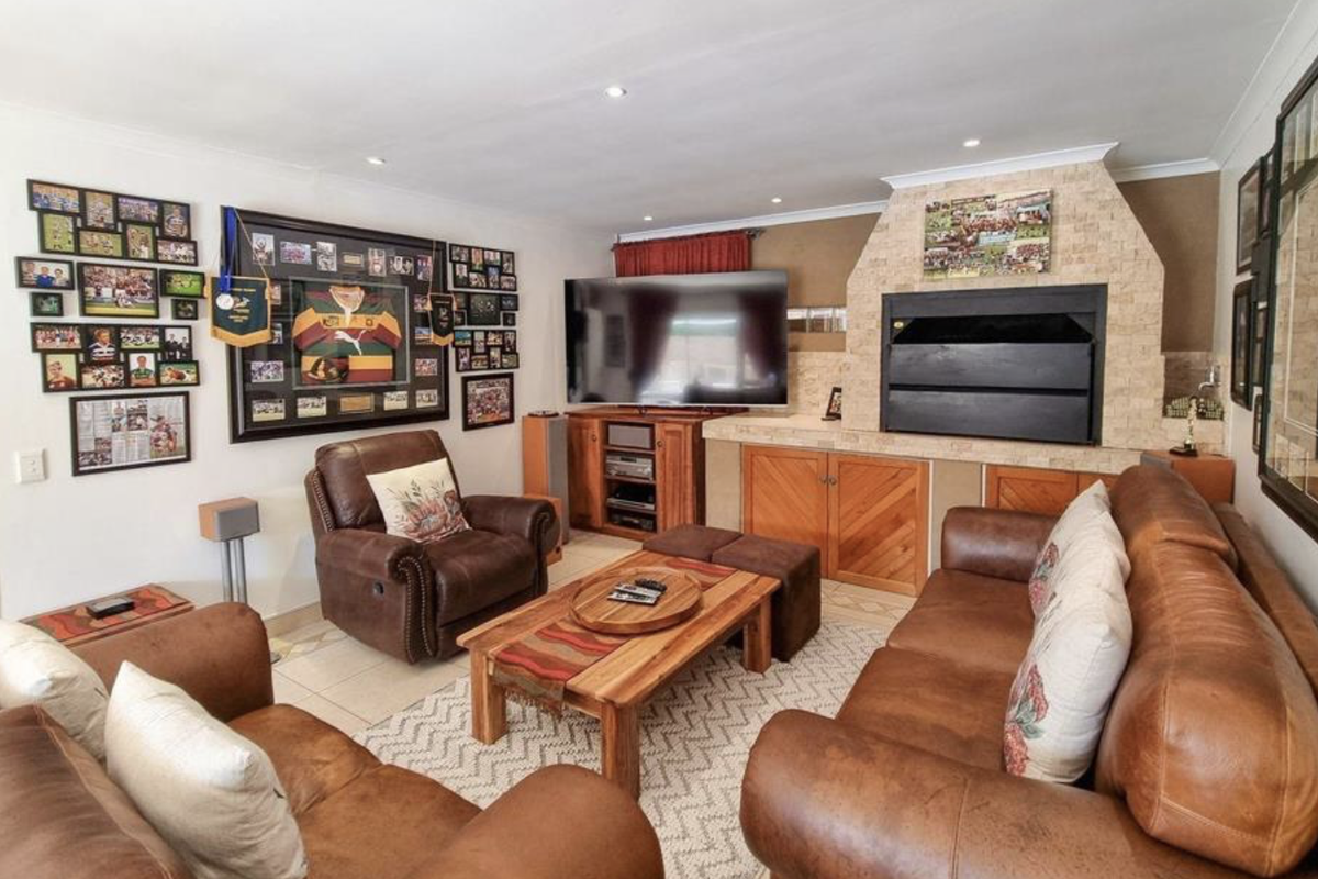A comfortable living room featuring a prominent stone-clad built-in fireplace, tiled flooring, and recessed lighting, creating a warm and inviting atmosphere.