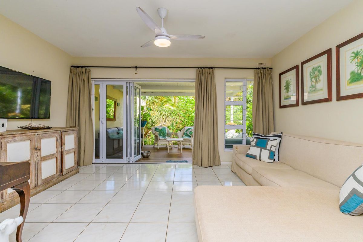 Spacious living room featuring tiled flooring, a ceiling fan, and large bi-fold doors providing seamless access to the outdoor patio area.