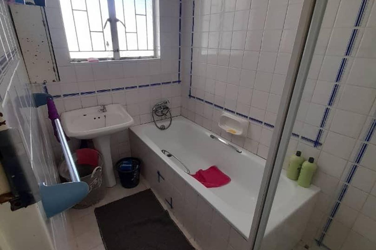 A functional bathroom featuring a bathtub, separate shower enclosure, and pedestal basin, finished with classic white wall tiling and blue accent detailing.