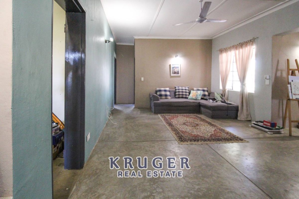 A spacious living room featuring polished concrete flooring, a ceiling fan, and neutral wall tones, providing a versatile area for relaxation.
