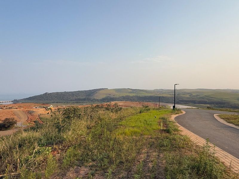 A scenic view overlooking a developing residential estate with paved roads, street lighting, and expansive landscape vistas.