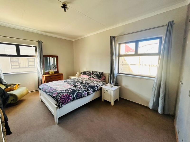 A standard bedroom featuring neutral wall finishes, carpeted flooring, and built-in cupboard storage with natural light from dual windows.