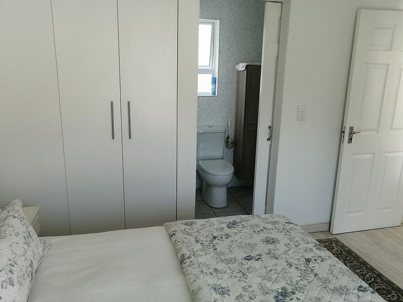 A bedroom featuring built-in cupboards and an adjoining en-suite bathroom with a toilet.