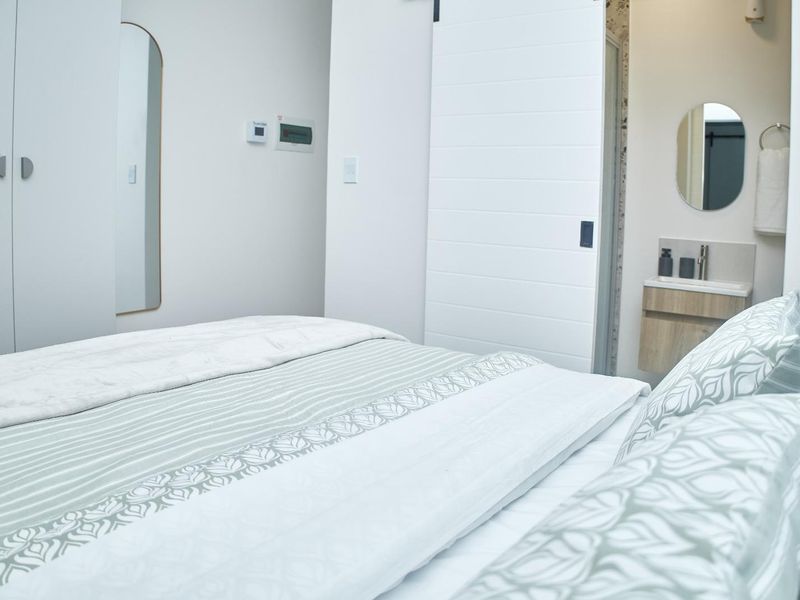 A modern bedroom featuring a built-in wardrobe and a sliding door leading to an en-suite bathroom with a vanity.