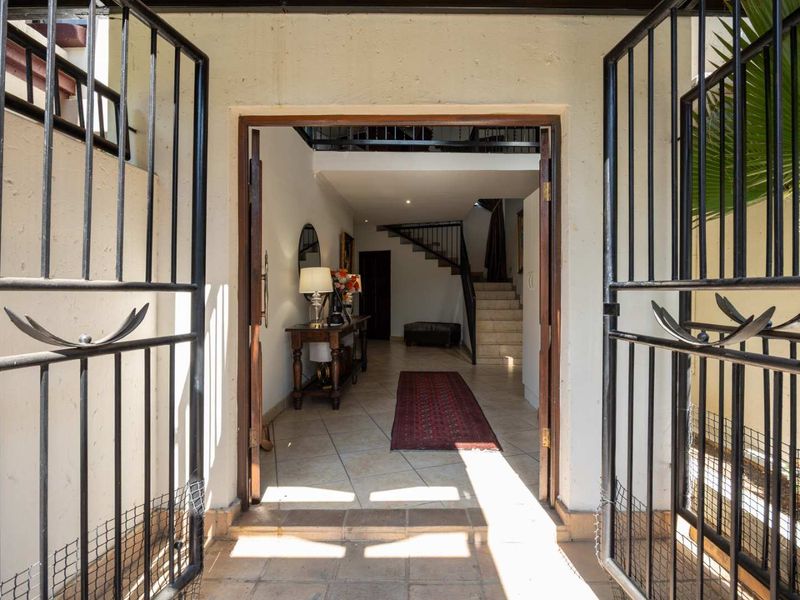 A welcoming entrance featuring a secure wrought iron gate, tiled flooring, and a staircase leading to the upper level.