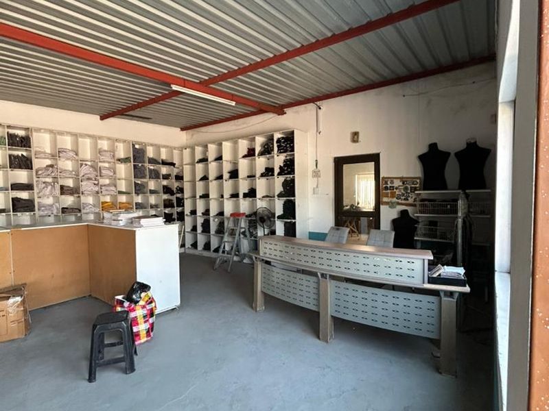 A functional utility or commercial workspace featuring extensive built-in shelving, a service counter, and an exposed industrial-style roof structure.