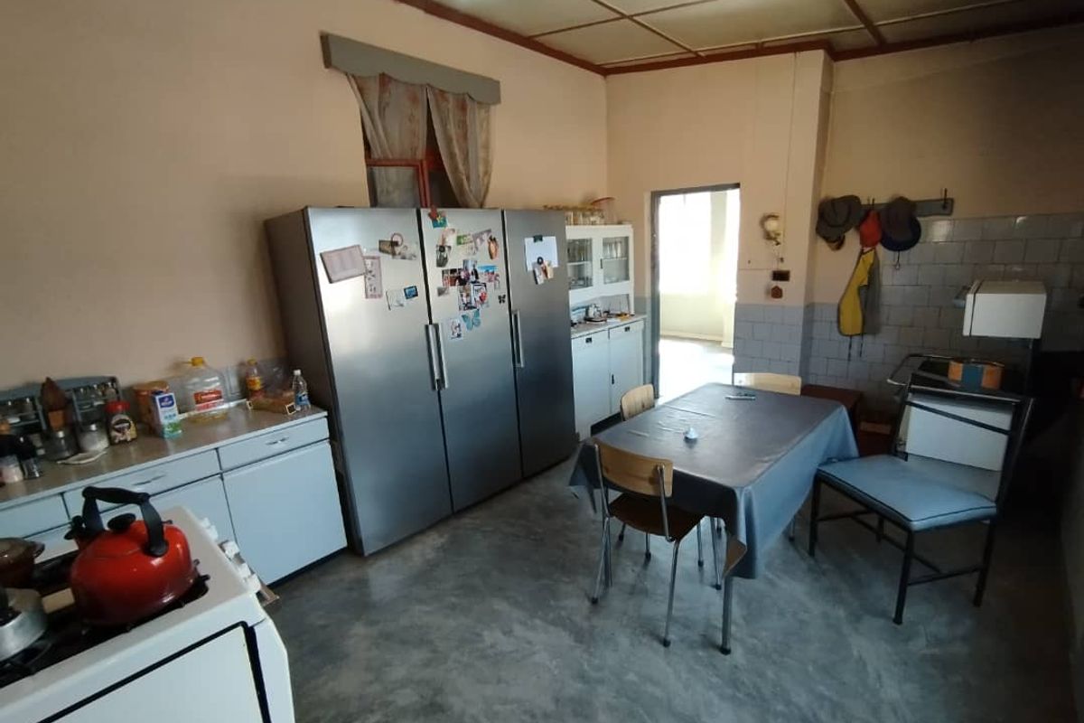 A functional kitchen area featuring basic cabinetry, tiled splashbacks, and concrete flooring, offering a practical space for daily meal preparation.